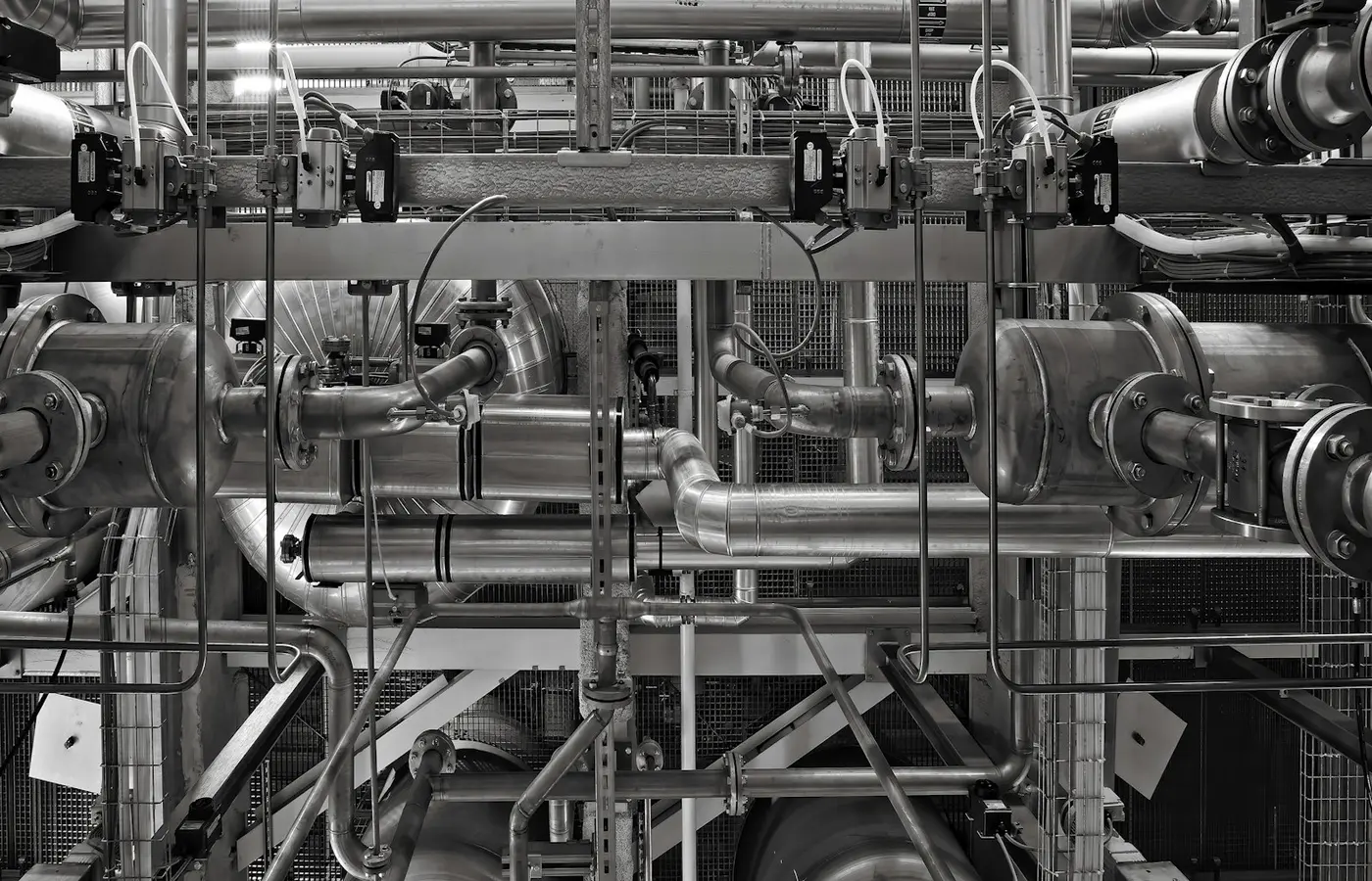 Industrial metal piping and valves in a factory, illustrating the piping context for pump arrangements.