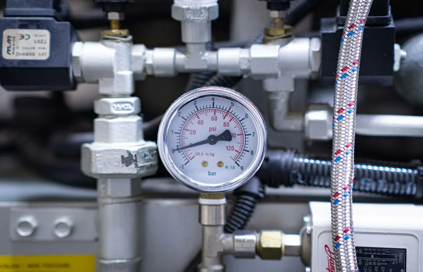 Close-up of a pressure gauge mounted on industrial equipment.